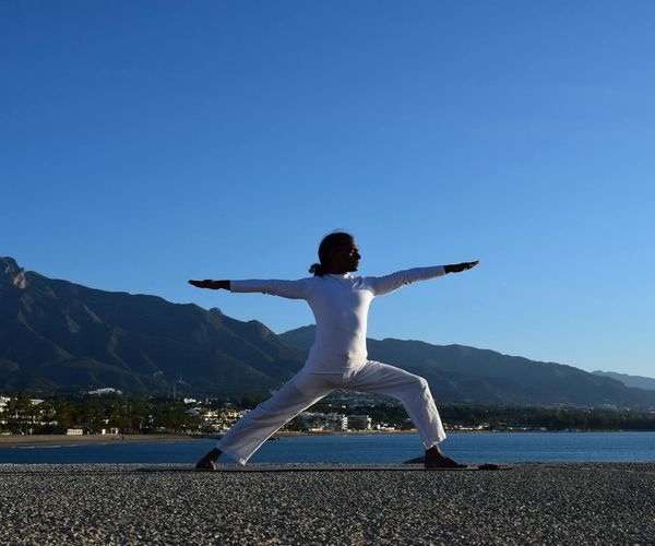 Silhouette of a person in a powerful warrior yoga pose.